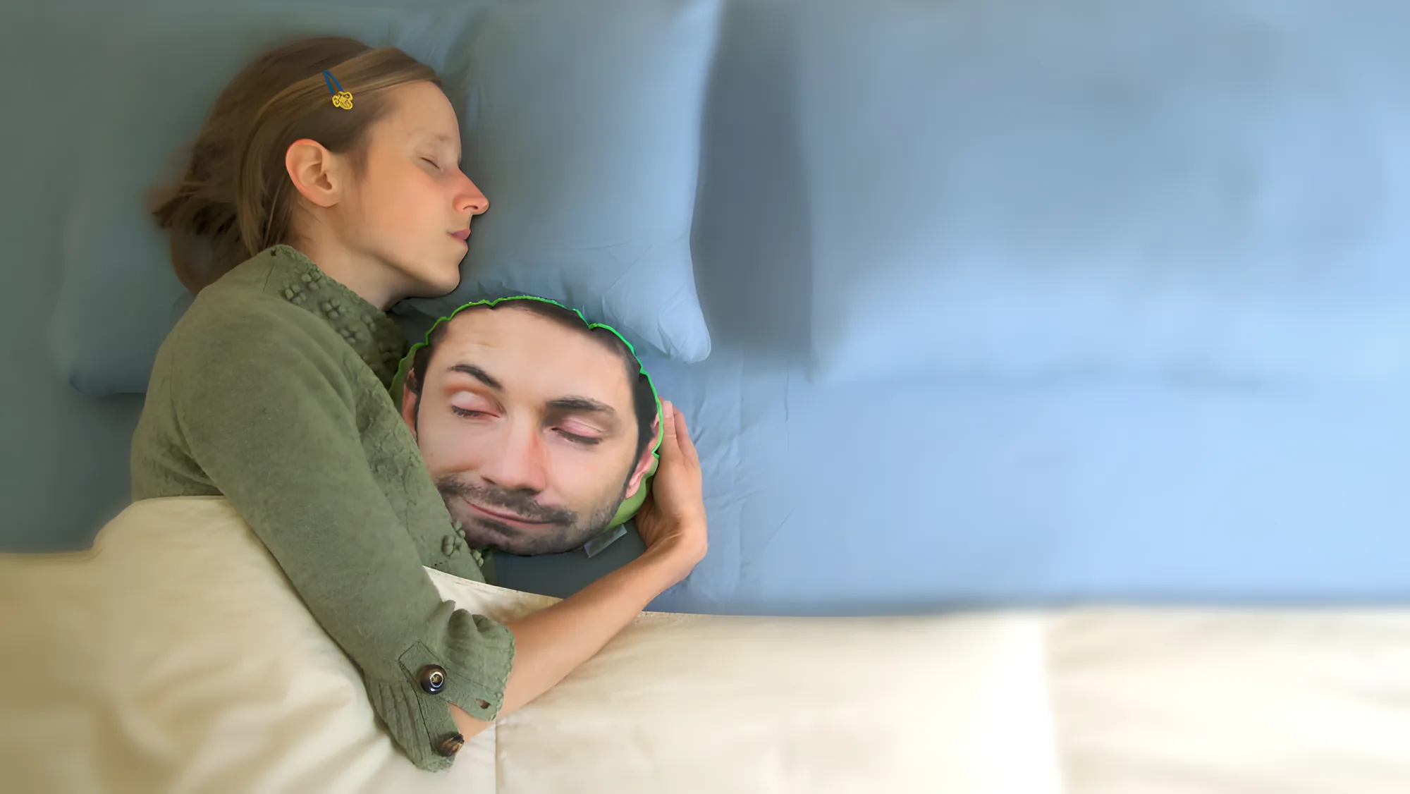 A woman asleep in bed, her arm around a pillow printed with a sleeping man's face.
